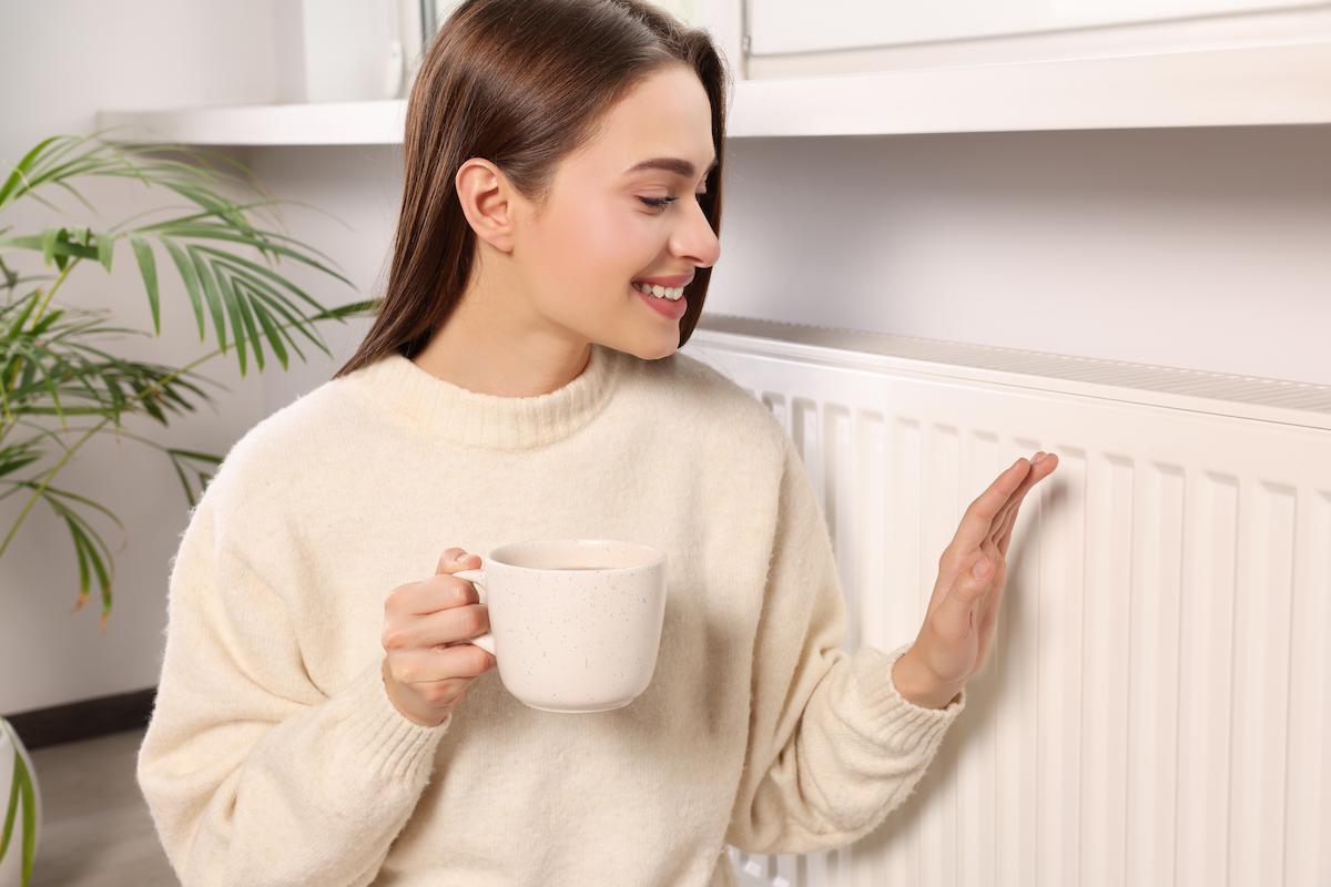 Femme qui se réchauffe près d'un radiateur