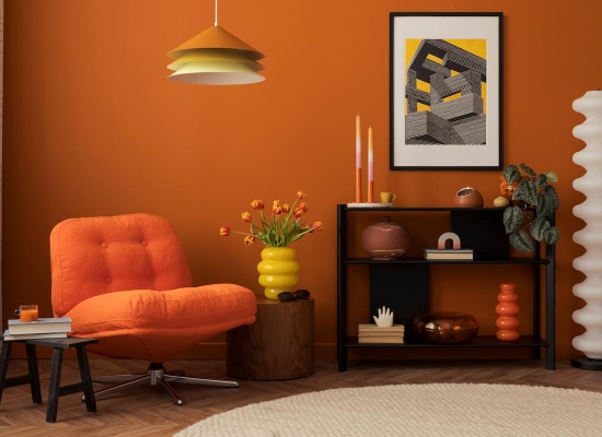 Salon aux murs orange, avec un fauteuil orange, des objets décos aux formes organiques, une lampe en métal et une table d'appoint en bois foncé