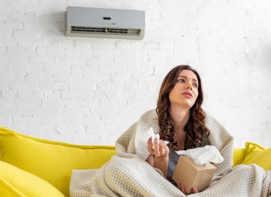 jeune femme pas en forme assise sous un climatiseur