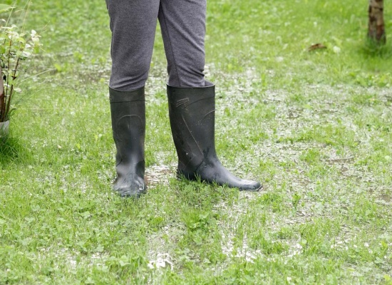 Personne avec bottes en caoutchouc dans un jardin détrempé
