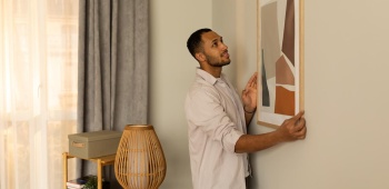 home accroche un tableau pour decorer son salon