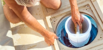 un homme nettoie le filtre de sa piscine