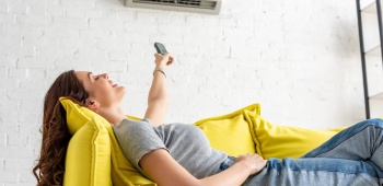 Une femme profitant de la fraîcheur de la climatisation allongée sur un canapé