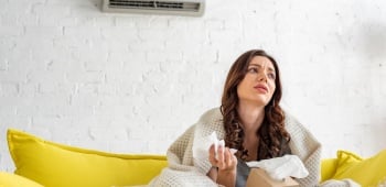 jeune femme pas en forme assise sous un climatiseur