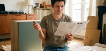 homme perplexe devant une notice d'assemblage de meuble