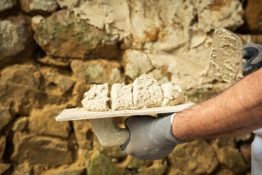 artisan construit un mur en pierres