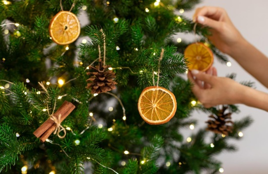 Un sapin de Noël décoré avec des pommes de pin et des tranches d'orange.