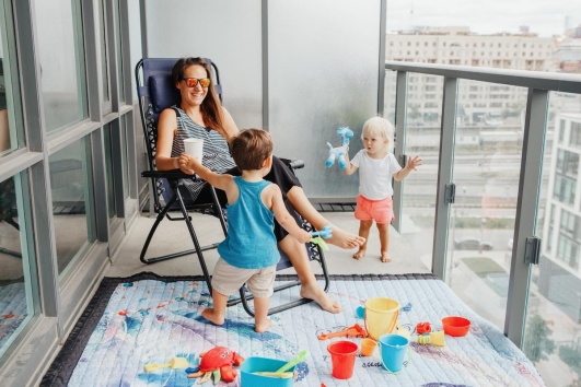 Enfants jouant sur un balcon sous la surveillance d'un adulte.