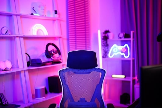 Chambre d'ado avec une chaise de gaming, des lumières LED et des étagères.