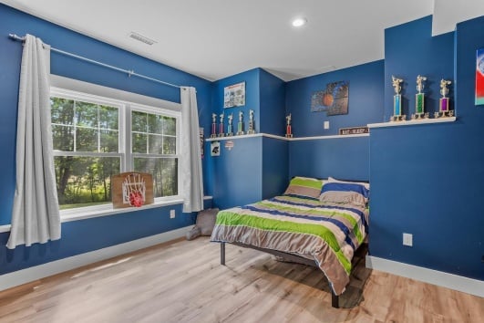 Chambre d'ado avec un panier de basket et des trophées. 