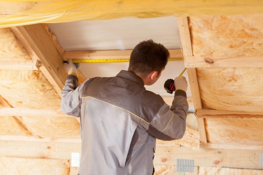 Artisan installant de l'isolant dans les combles