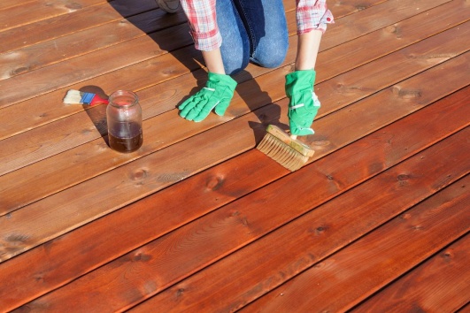 Personne ne train d'appliquer un produit d'étanchéification sur une terrasse en bois