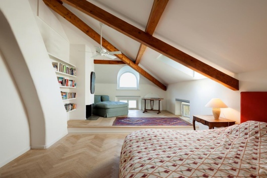 Chambre avec espace lecture dans des combles avec poutres visibles
