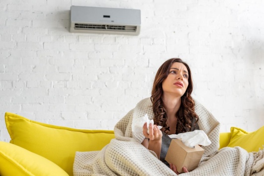 jeune femme pas en forme assise sous un climatiseur