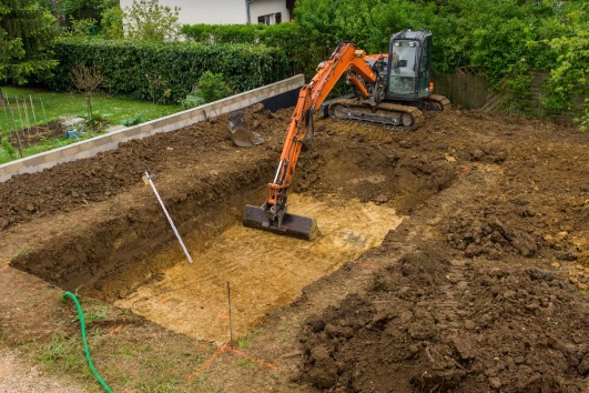 Pelleteuse qui creuse une piscine dans un jardin