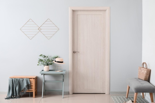 Entrée aux murs gris avec une porte en bois clair