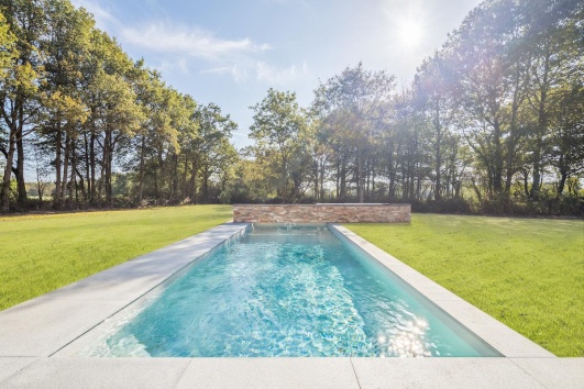 Piscine rectangulaire, entourée de gazon, dans un jardin