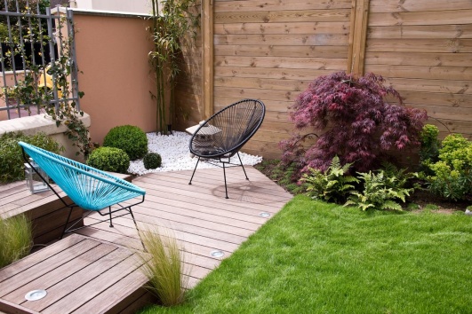 Petite terrasse en bois dans un jardin avec deux fauteuils