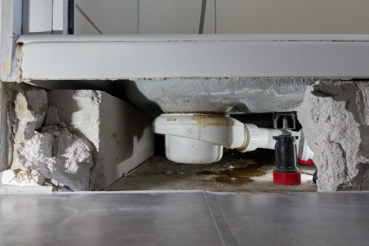 Vue du dessous d'un receveur de douche qui fuit