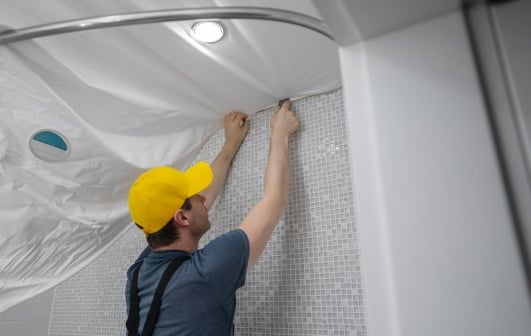 artisan installant un faux plafond pour rénover une salle de bain