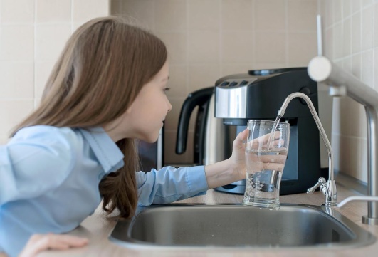 fillette qui prend un verre d'eau pur grace a son osmoseur