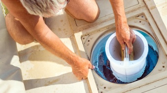 un homme nettoie le filtre de sa piscine