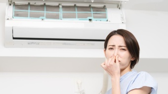 Femme qui se bouche le nez devant un climatiseur