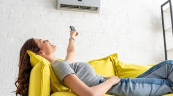 Une femme profitant de la fraîcheur de la climatisation allongée sur un canapé