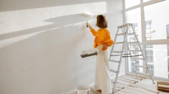 Femme qui peint un mur en blanc avec un rouleau